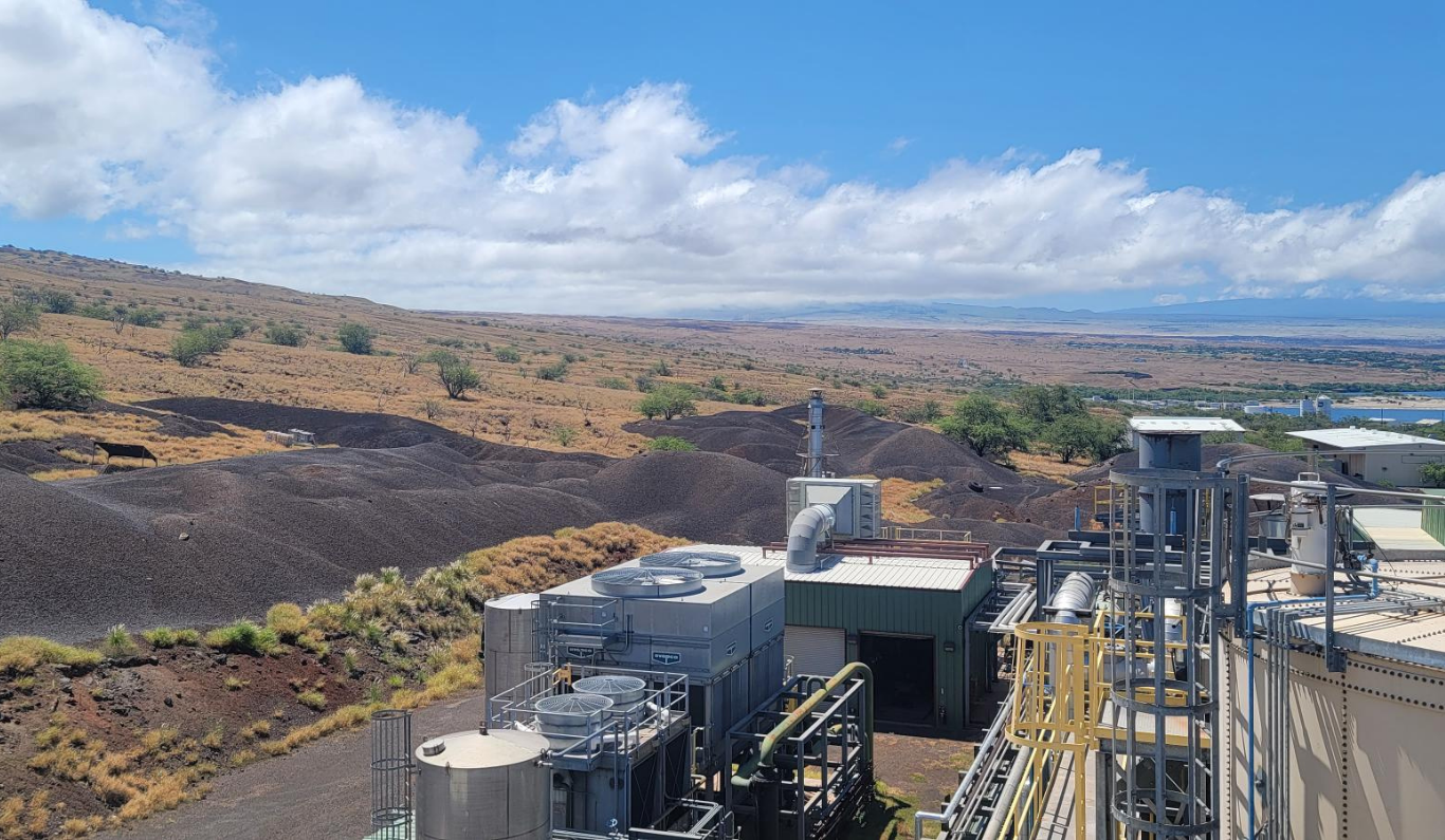 Mauka view from the AgEnergy Hawai‘i facility showing pyrolysis stacks, cooling units, and the open Kohala landscape stretching toward Mauna Kea